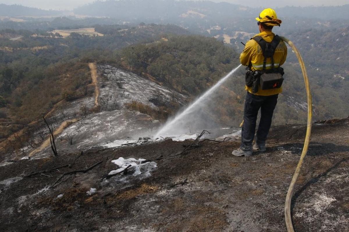 Kit Hentzen sprays foam on hot spots at the Chimney Fire near Oak Shores in July.