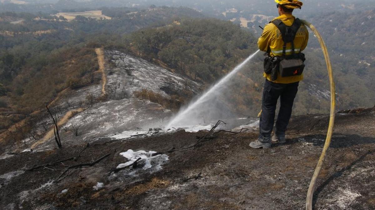 Kit Hentzen sprays foam on hot spots at the Chimney Fire near Oak Shores in July.