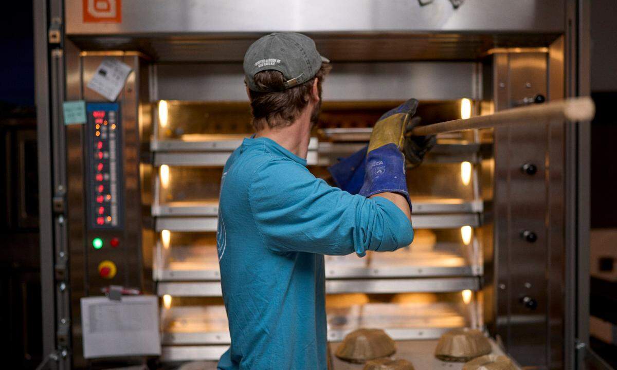 Jordan Hay, a baker at Bread Bike bakery in San Luis Obispo, pulls some fresh goodies out of the oven.