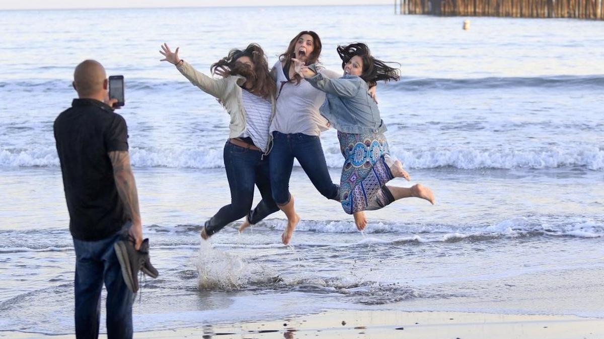 A group of friends gathers on Avila Beach after a day of celebrating the impending wedding of mutual friends Taylor Matthews and Corey Beck. Here, Rodney Pestano takes a photo of Angelica Pestano, left, Matthews and Courtney Mase, all from the San Francisco Bay Area.