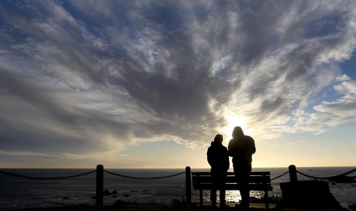 Emma Sandquist, left, and Matt Theis, both from San Luis Obispo, watch a late afternoon sunset at Margo Dodd Park in Shell Beach.