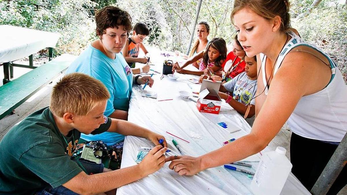 Austin Hall, left, gets some instruction from Erica Mundell-McGilvray during a tie-dye tile-making class at Camp Hapitok in July.