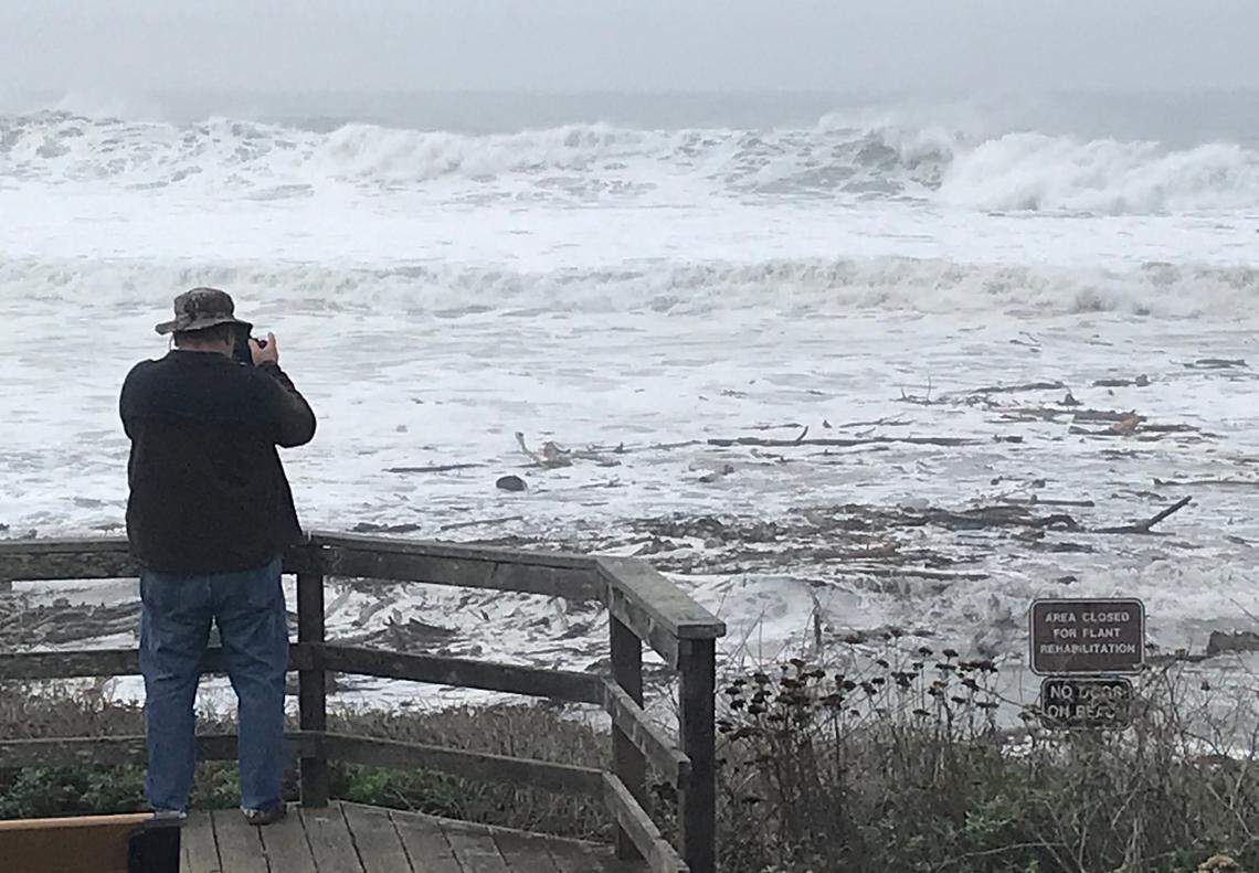 At the Santa Rosa Creek overlook vista point on Moonstone Beach in Cambria, Jim Keally of Arizona captures images of big waves Thursday, Dec. 28, 2023, as the pounding ocean, carrying lots of driftwood, meets flowing creek water. 