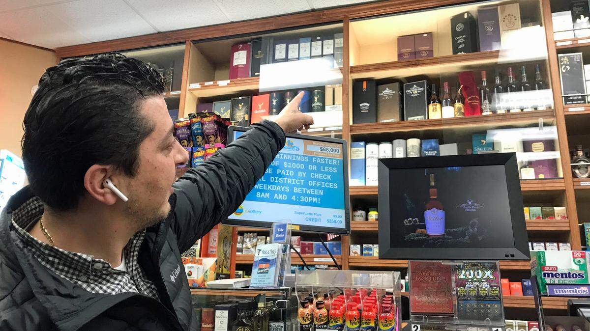 Joseph Ayoub points to the empty spots where pricey bottles of liquor were stolen early Wednesday, Jan. 24, 2024, from Bob & Jan’s Bottle Shop in Cambria.