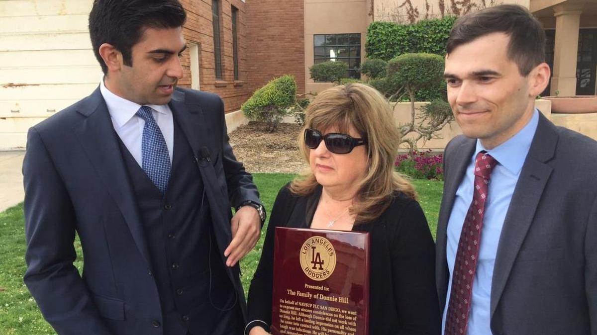 Diane Hill, center, holds a plaque given to her by co-workers of her son Donald “Donnie” Hill after his death. Attorneys Neil Gehlawat, left, and Thomas Seabaugh announced a pending lawsuit against the city of Lemoore.