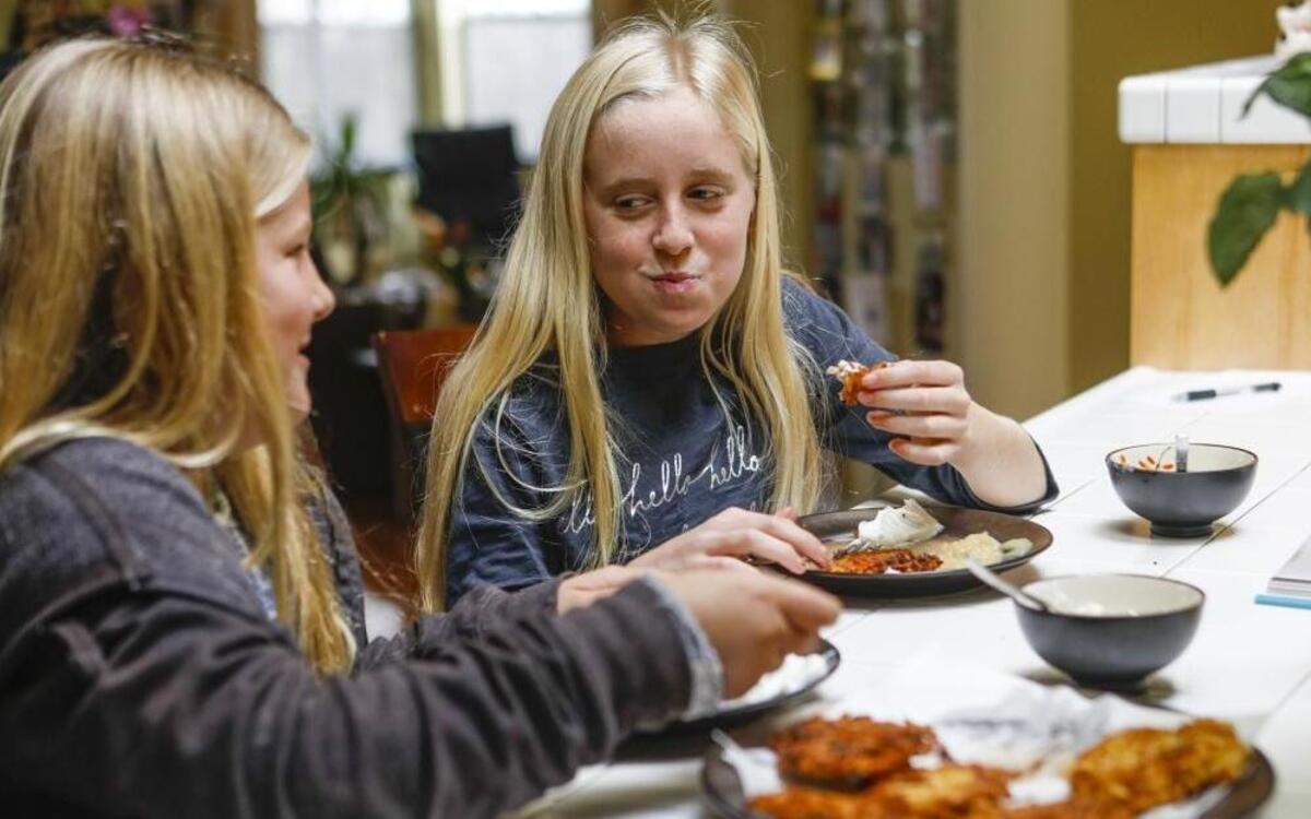 Lindsey Giannini, 10, left, got to taste latkes for the first time while Aubrey O’Leary pronounced her preference for a crispy potato pancake. The start of Hanukkah was Christmas Eve this year. The O’Leary family makes latkes as part of their traditional celebration.