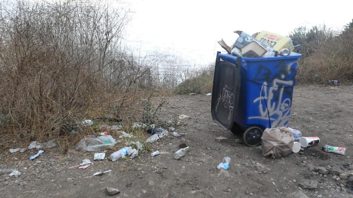 Trash is littered around an overflowing garbage can on the blufftop at Pirate’s Cove in early September.