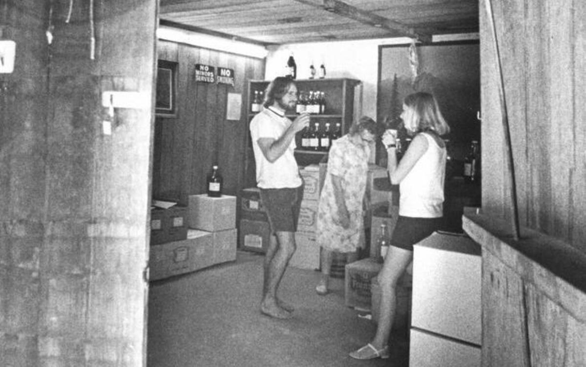 Tourists taste samples of Rotta wine in the 7,000-gallon tasting room. The room is a rebuilt wine cask, complete with a pale pink crust of cream of tartar on the ceiling — the remains of the last time the cask was used for wine. Tartar has to be scraped from wine casks each time they are emptied. Mrs. Romilda Rotta, center, supervises the sampling.