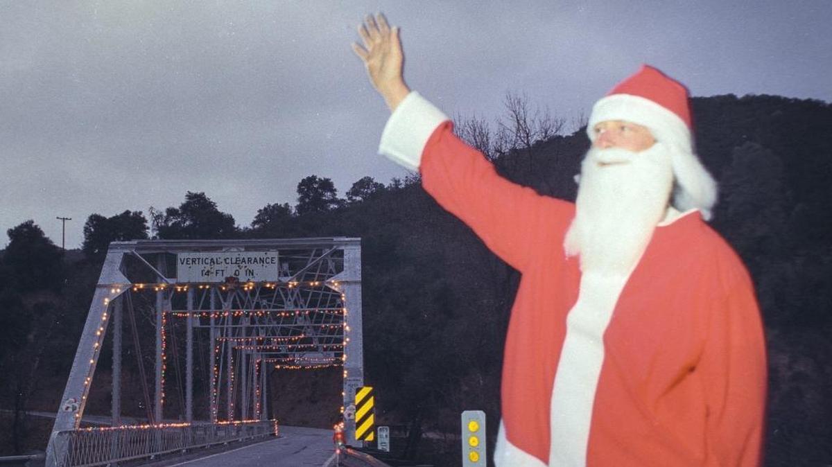 Santa’s “helper” Jim Broadfoot waves to passers-by in December 1992 at the bridge he decked out for Christmas on Highway 58 east of Santa Margarita.