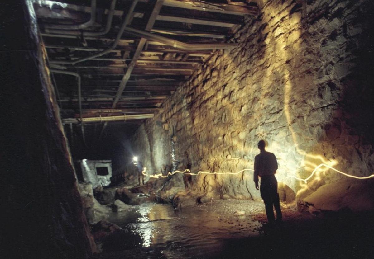 UNDER HIGUERA STREET: Mike McCluskey, SLO City public works director, leads a tour in December 1995, where San Luis Creeks flows under Higuera Street. Bishop Peak granite was quarried to make the walls. The city rebuilt the 87-year old bridge work. This is a time exposure using flashlights and strobe carried by the photographer.