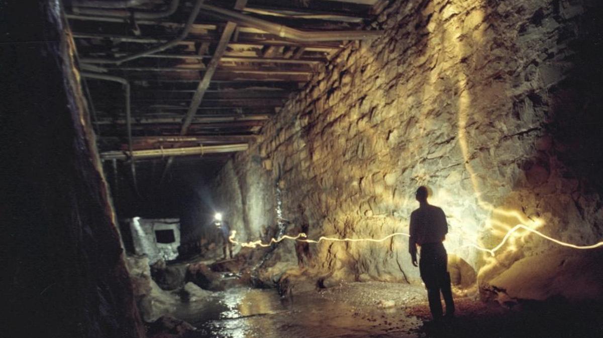 UNDER HIGUERA STREET: Mike McCluskey, SLO City public works director, leads a tour in December 1995, where San Luis Creeks flows under Higuera Street. Bishop Peak granite was quarried to make the walls. The city rebuilt the 87-year old bridge work. This is a time exposure using flashlights and strobe carried by the photographer.