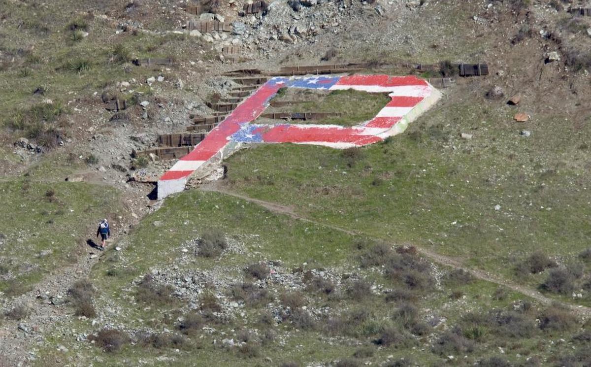 A hiker takes the trail to the Cal Poly P, which was painted red, white and blue in December 2014.