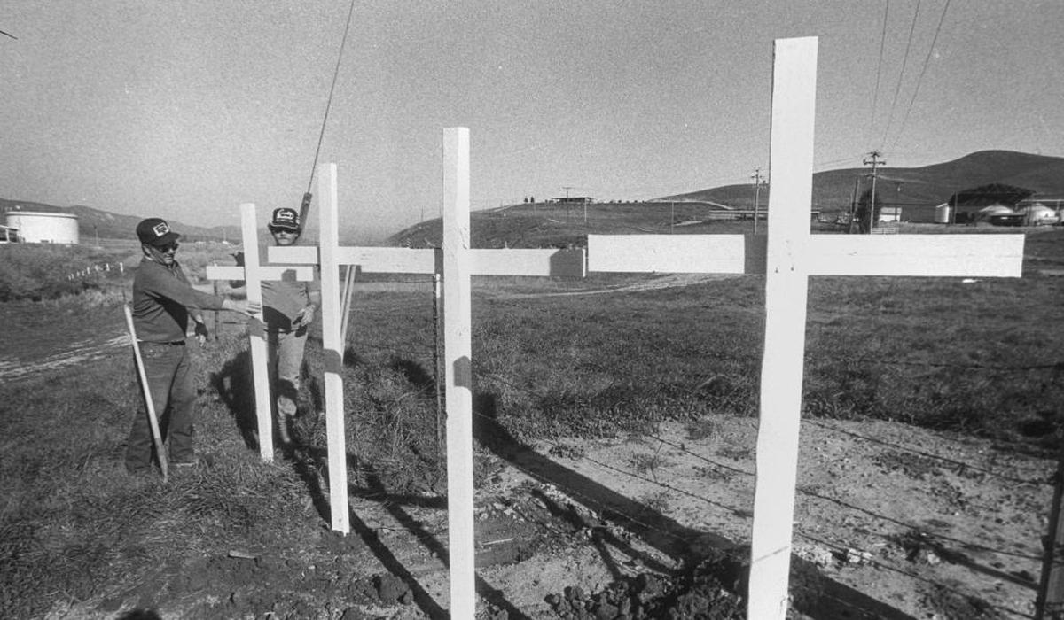 Richard Hollister, left, and Curtis Tara erect white crosses along Highway 46 to mark the spot where a car-truck crash killed five in 1988.