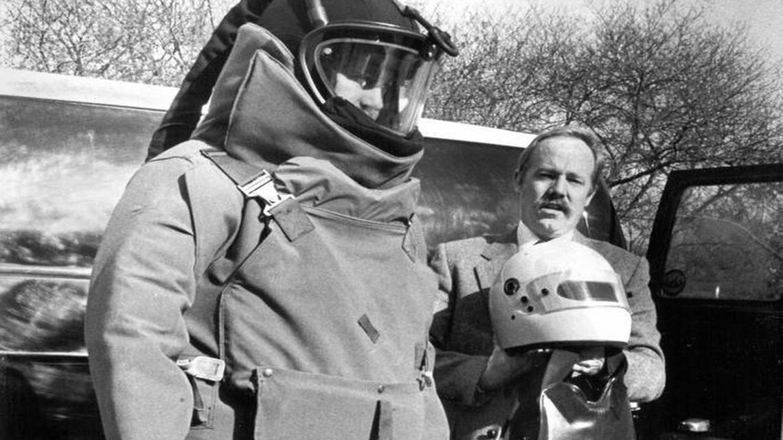 Gary Hoving models the bomb squad’s new $8,000 suit in January 1987, while Jim Mulhall holds the old protection gear.