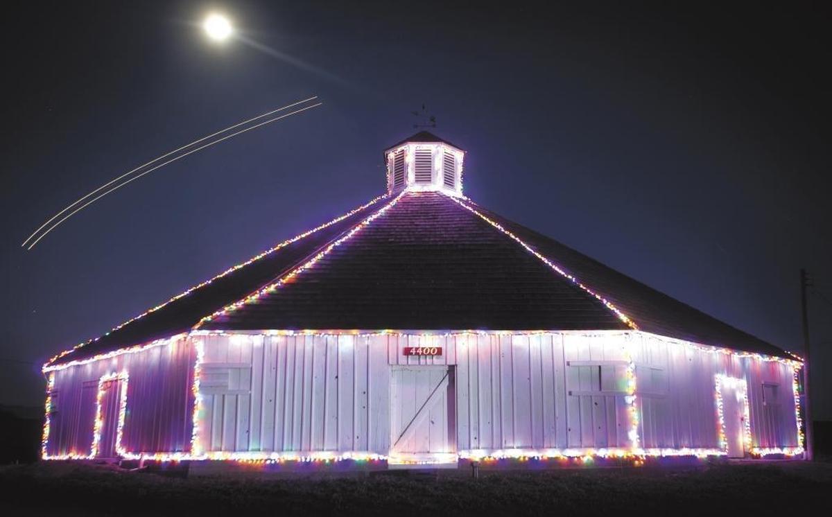 A rising moon and airplane lights compete with the holiday lights on the Octagon Barn in December 2011.