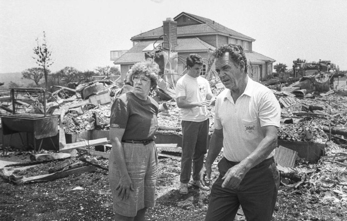 Kathy Mackins visits the former site of her house in Sierra Madre Heights with Al Escalera, right. Five of 12 homes in the Santa Barbara development were lost in the aftermath of the Painted Cave Fire in 1990.