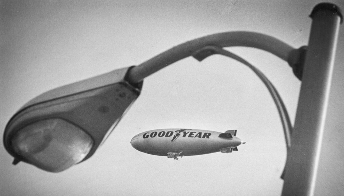 A Goodyear blimp can be seen passing over San Luis Obispo in January 1977. It is framed by a Cal Poly light pole.