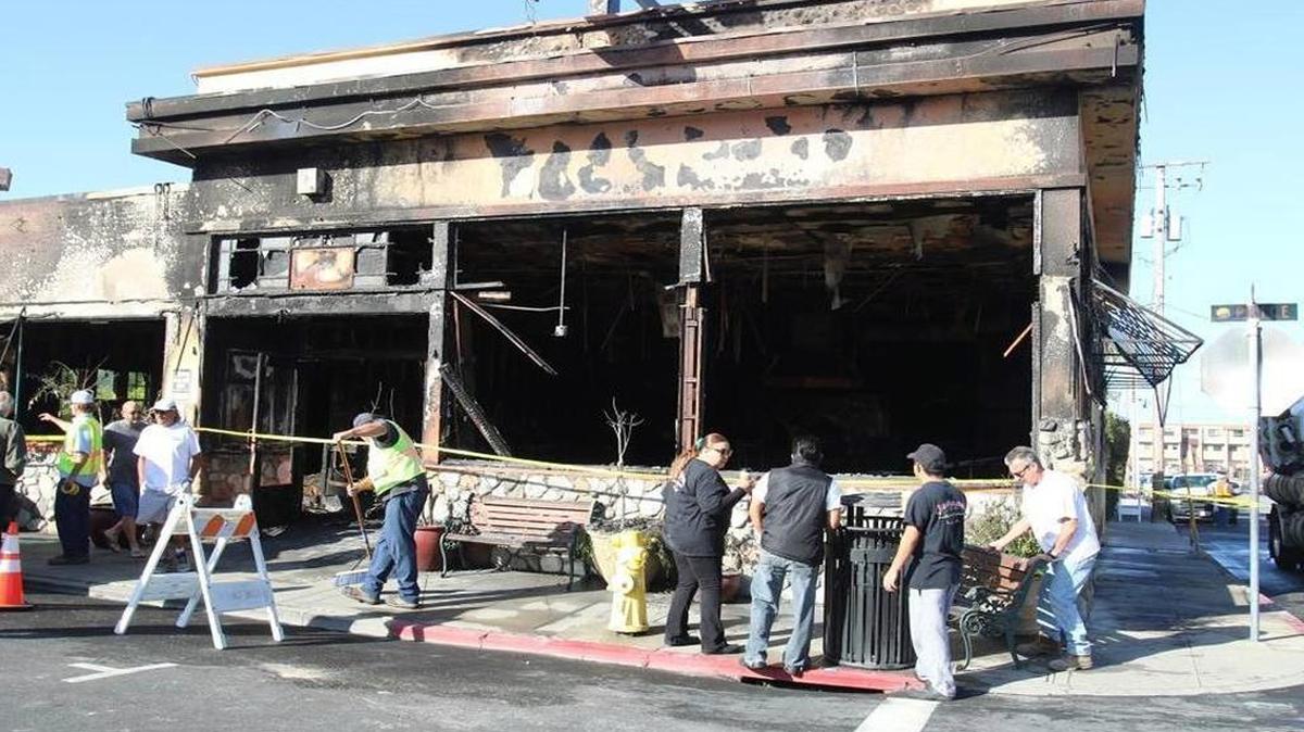 Employees watch as crews clean up the sidewalk after an early-morning fire destroyed Giuseppe’s Cucina Italiana in Pismo Beach on June 25.