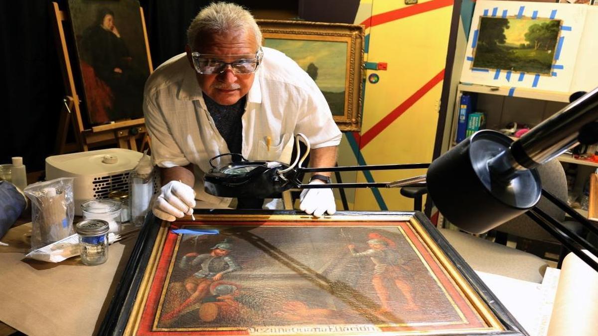 Nageh Bichay cleaning a Station of the Cross painting.