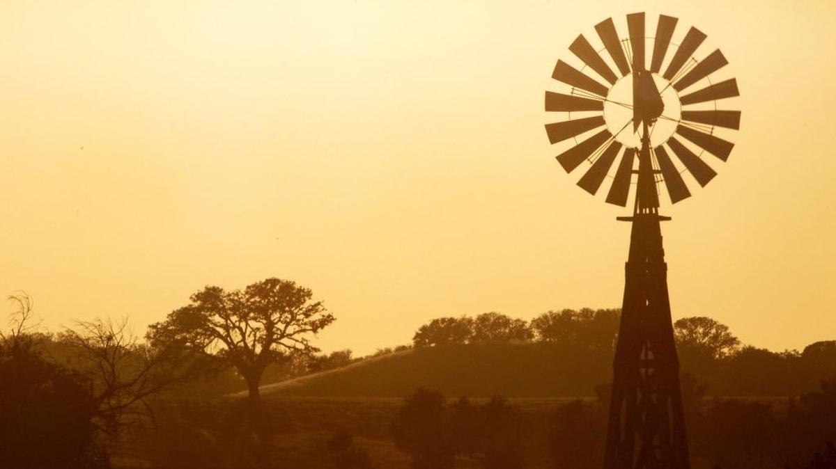 On a recent evening, the sky turns orange behind a windmill and oaks near Creston shortly before sunset along Highway 41.