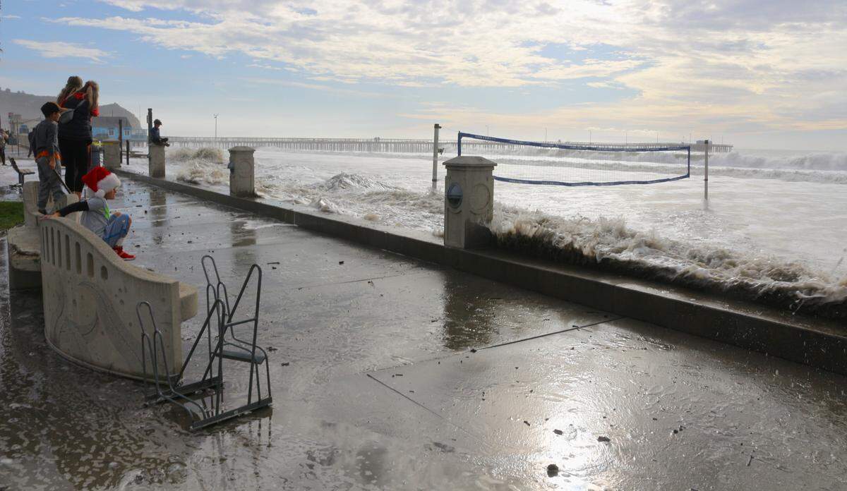High surf runs all the way up Avila Beach to the sidewalk as visitors take in the sight on Thursday, Dec. 28 2023.
