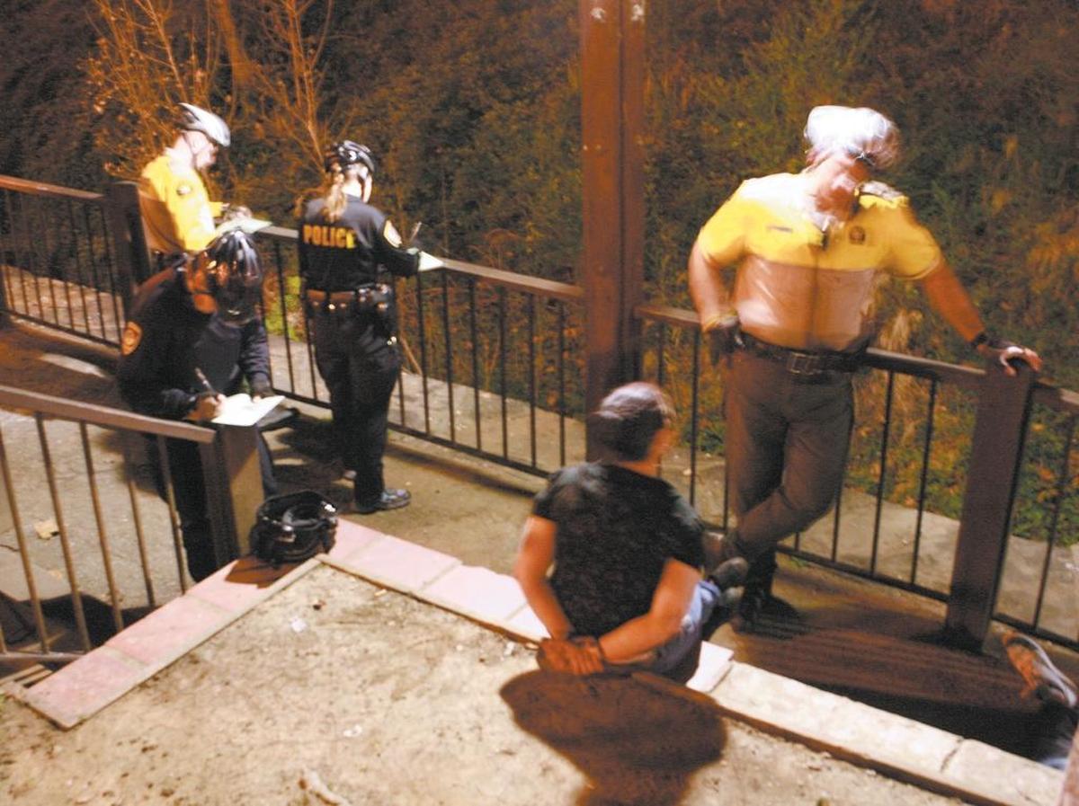 Officers from the Sheriff’s Office and San Luis Obispo Police Department process alcohol violations in downtown San Luis Obispo near the creek at Nipomo Street.