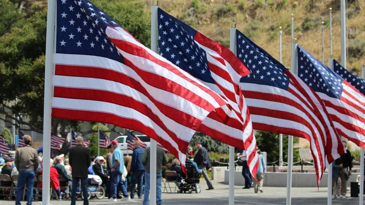American flags fly in a line along the perimeter of the Veterans Memorial Building parking lot in Cambria.