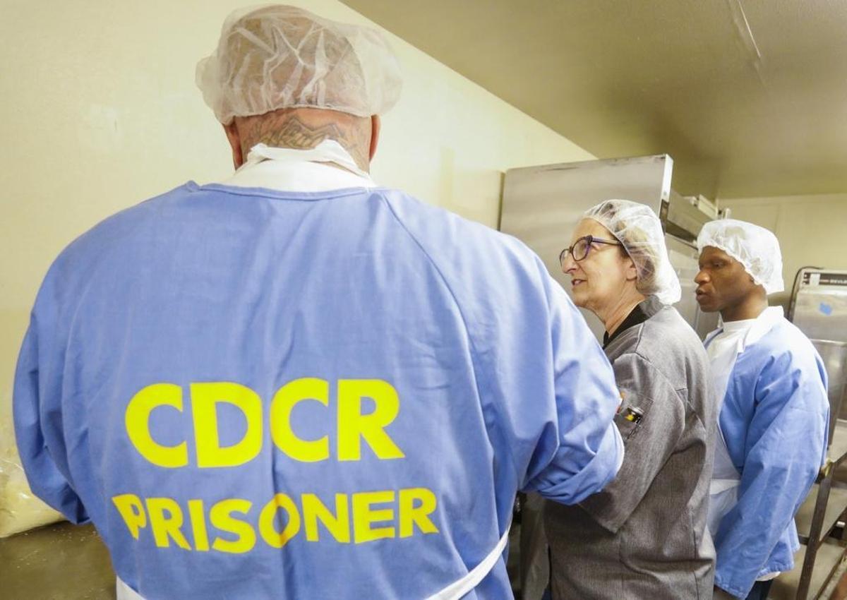 A cooking instructor from Cuesta College advises California Men’s Colony students in the prison’s new culinary arts program. The prison graduated its first class of cooking students on Friday.
