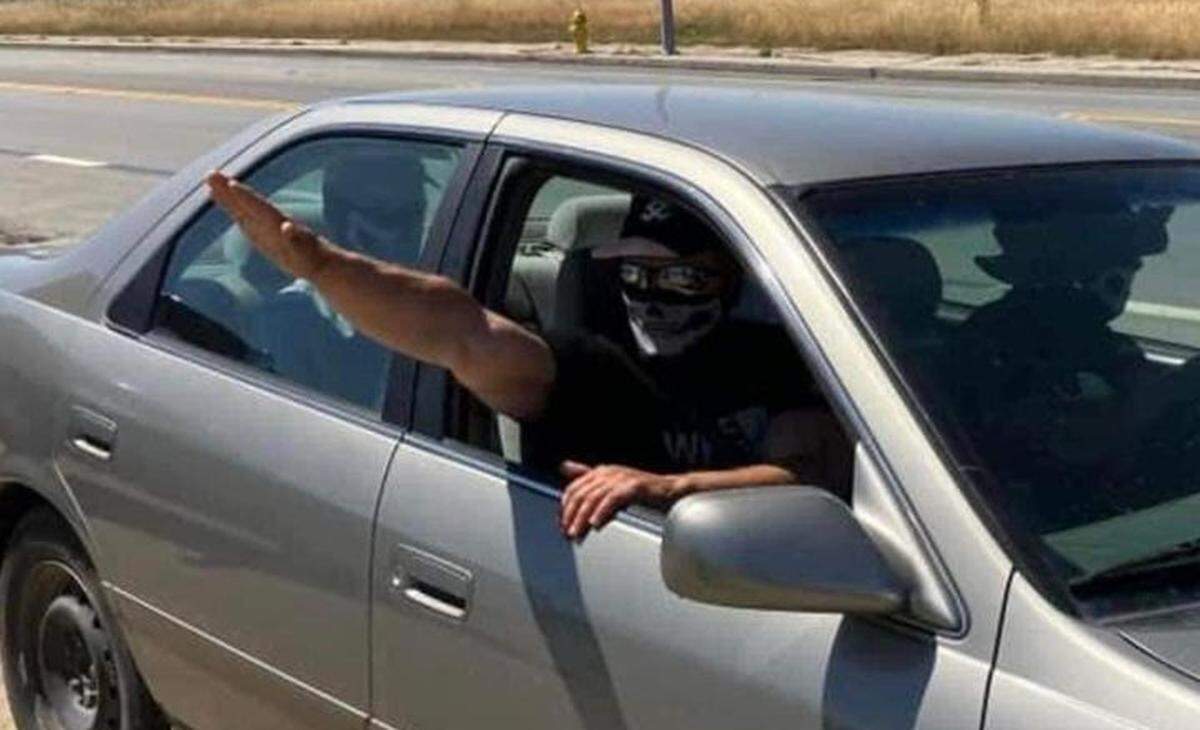 Several men with masks again held up an “Embrace white pride” flag on the Vineyard Drive Highway 101 overpass on Saturday, May 13, 2023. One of the men gives a Nazi salute as the group left in a silver sedan.