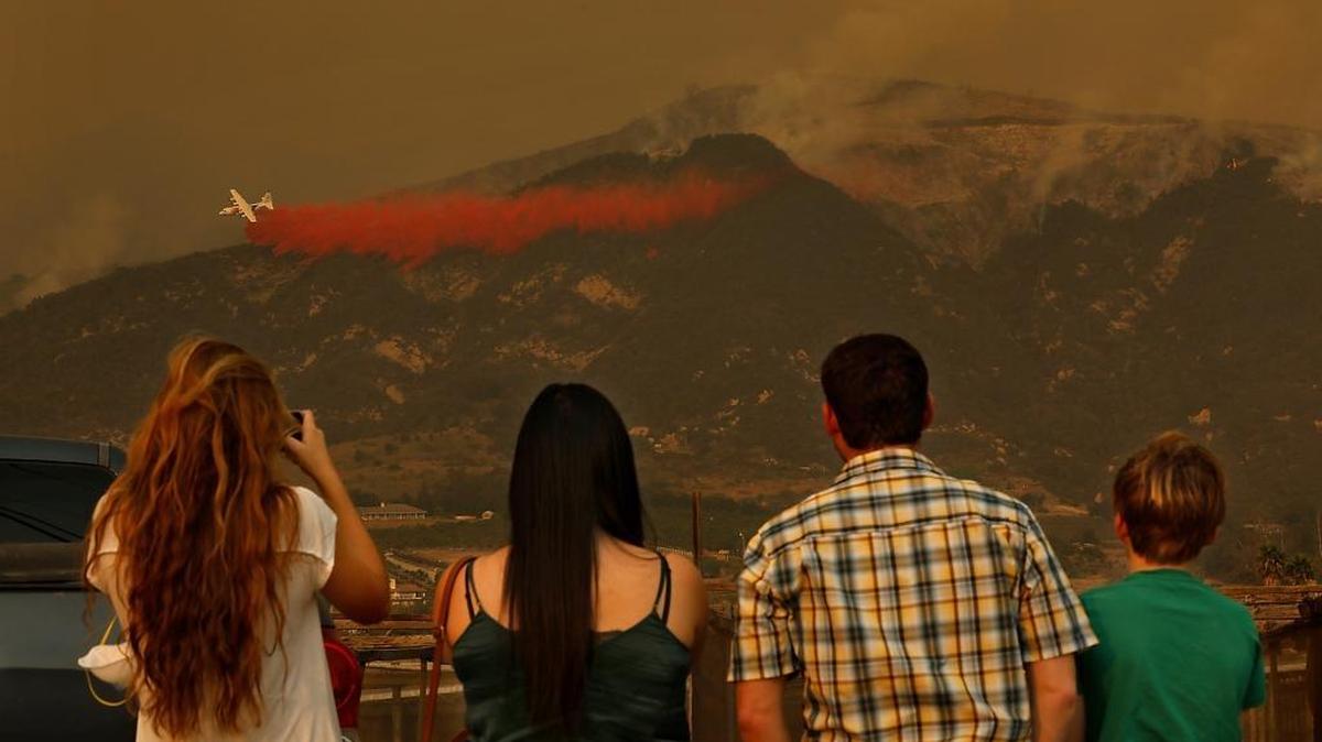 People watch as a plane drops fire retardant on the Thomas Fire in Carpenteria on Dec. 11, 2017.