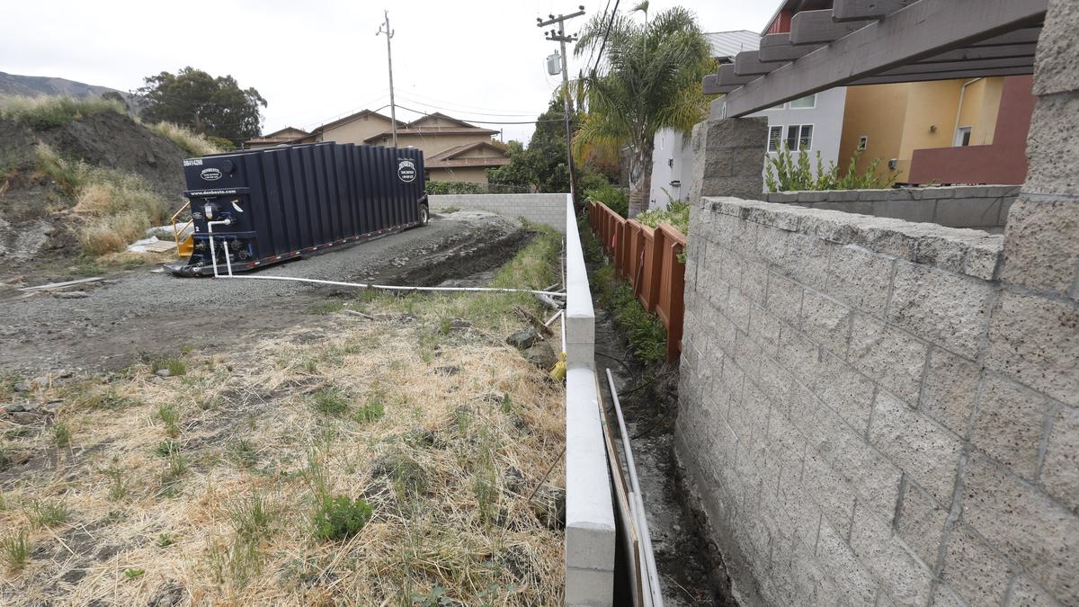 Neighbors of a property under development on Laurel Lane in San Luis Obispo are concerned about flooding after they say construction workers hit a high water table that sent a steady flow of water under a retaining wall and into an alley between their parcels.