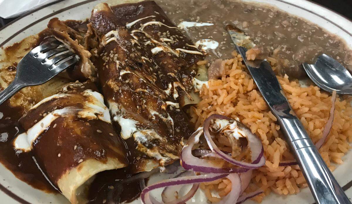 Three Cambria Cafe chicken enchiladas are draped with a dark, rich, housemade mole sauce that’s both slightly sweet and spicy.
