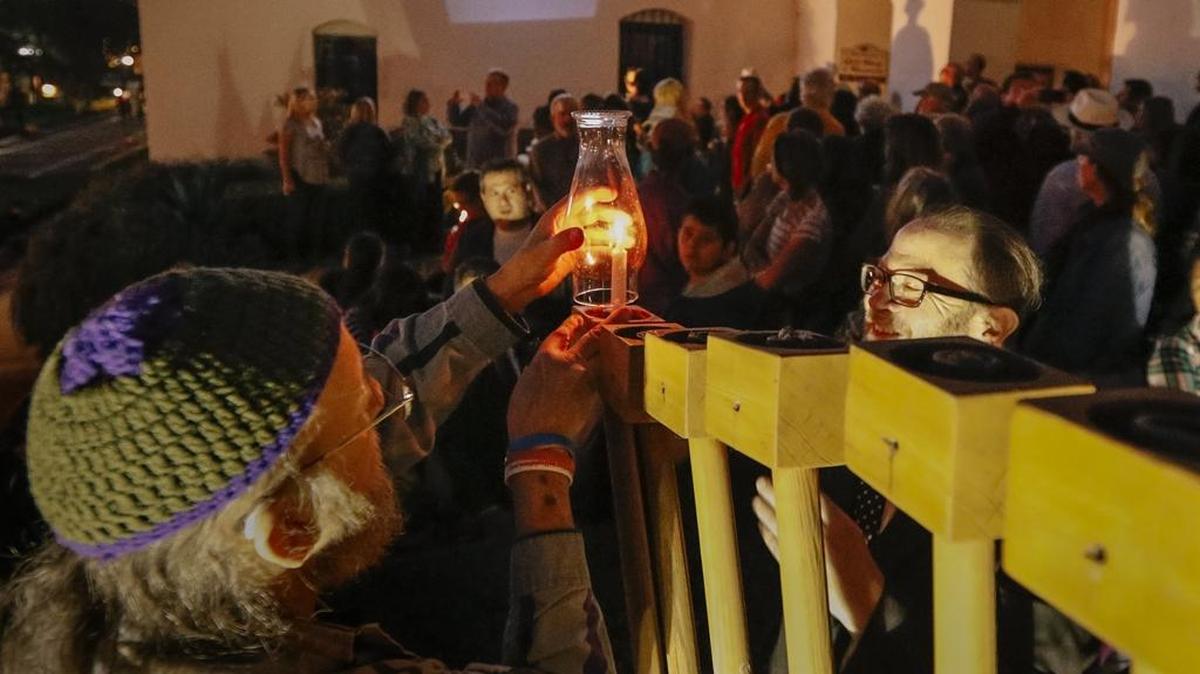 Norman Stone, left, and San Luis Obispo County Supervisor Adam Hill, light a candle on the menorah in front of the Mission for the first day of Hanukkah.