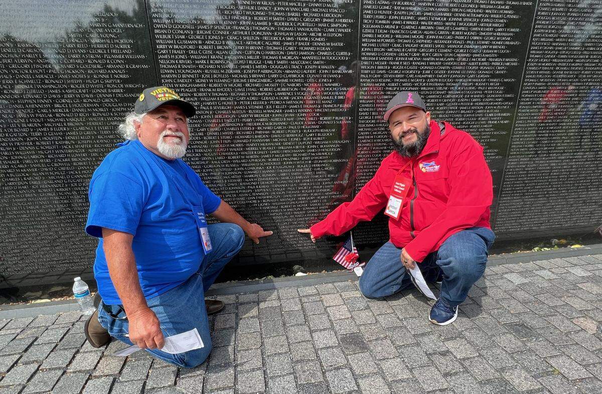 Wayne Perez and Vincent Garcia point out a name on the Vietnam War Memorial in Washington, D.C., during the Honor Flight tour on Apri. 25, 2023.