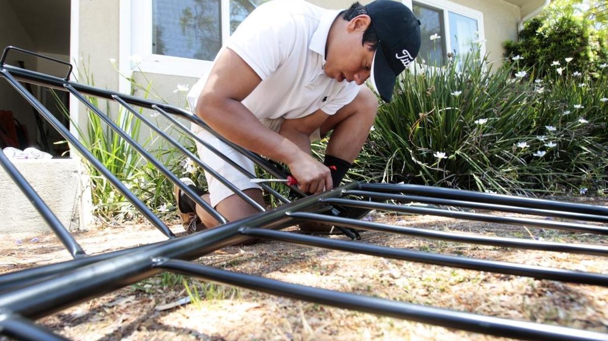 Gonzalo Berluzconi helps his sister move out by taking apart furniture in the neighborhood next to Sierra Vista Regional Medical Center. She graduated from Cal Poly this past weekend; he graduated from another university.