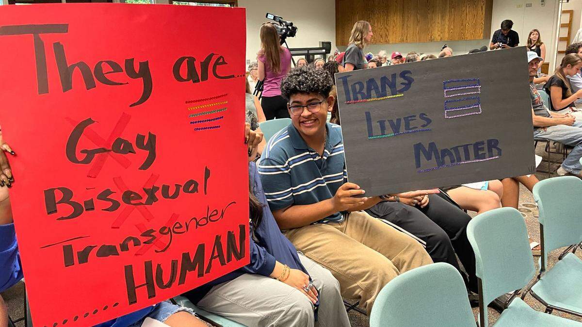 Members of the audience hold signs supporting LGBTQ+ students at the Paso Robles school board meeting on Tuesday. The board approved a resolution protecting traditional, gender-specific titles.