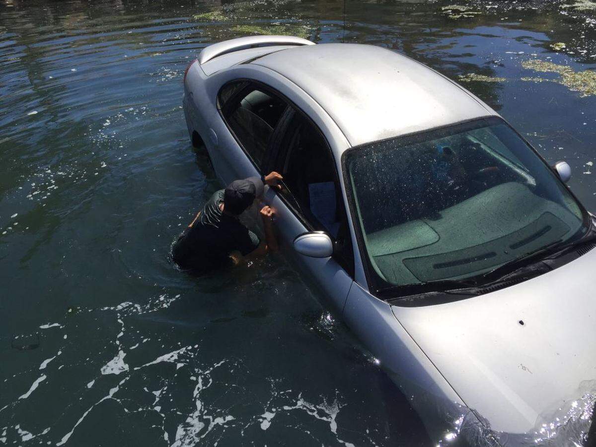 A Good Samaritan works to rescue a driver from his car after it plunged into the waters of Morro Bay on Tuesday morning.