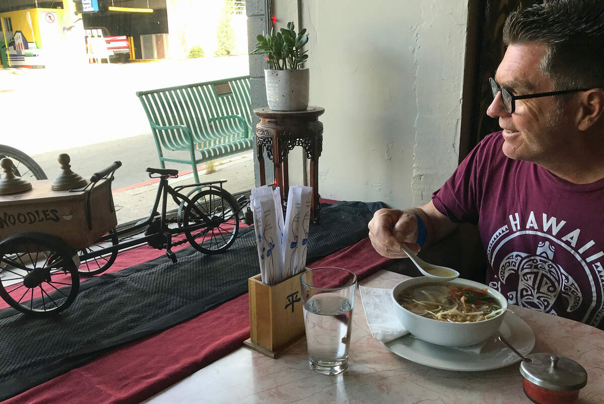 As he digs into his bone-broth chicken soup, visitor and former San Luis Obispo resident David Mott enjoys the view from the window table at Mee Heng Low restaurant on Wednesday, Oct. 25, 2023. The cyclist, who was in town visiting his parents, said he’d learned to love the decades-old Chinese restaurant while attending Cal Poly.