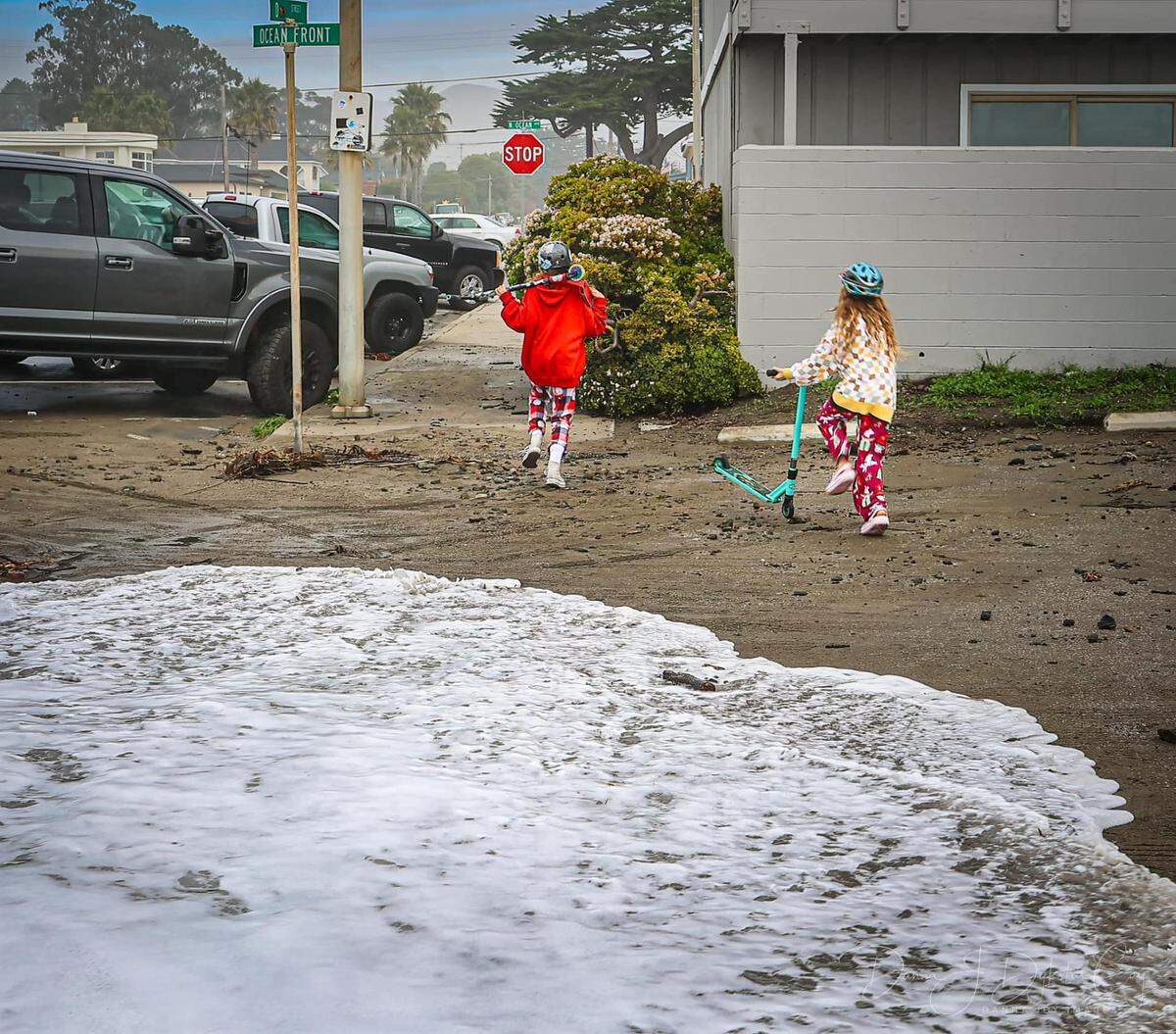 Children run from high surf flooding the streets of Cayucos on Thursday, Dec. 29, 2023.