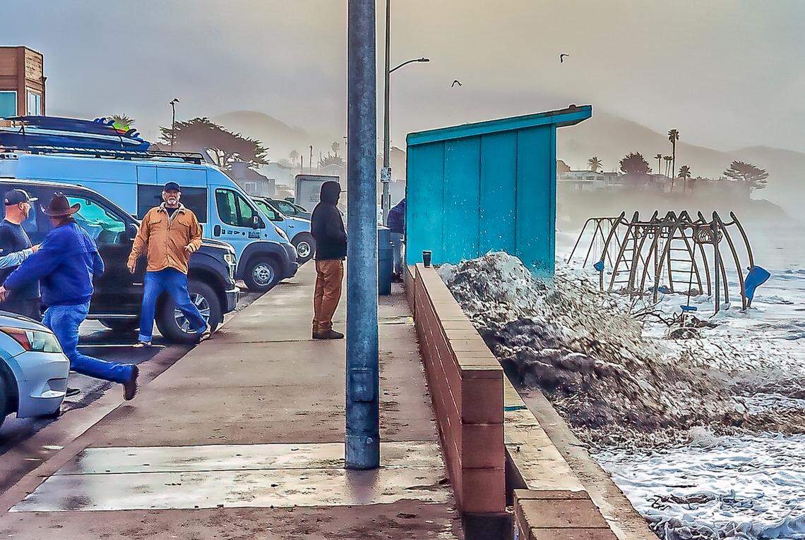 A wave crashes against the sea wall in Cayucos as spectators dash out of the way on Jan. 5, 2023.