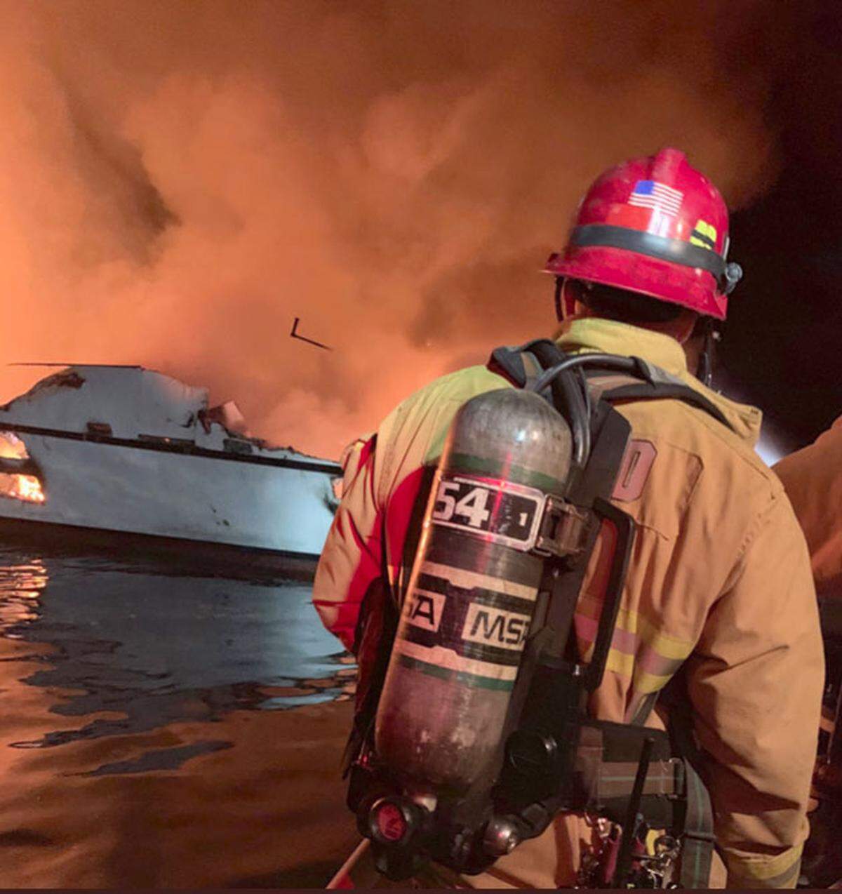 A firefighter sprays water on the Conception dive boat, which caught fire and sank on Labor Day 2019 near Santa Cruz Island, killing 34 people.