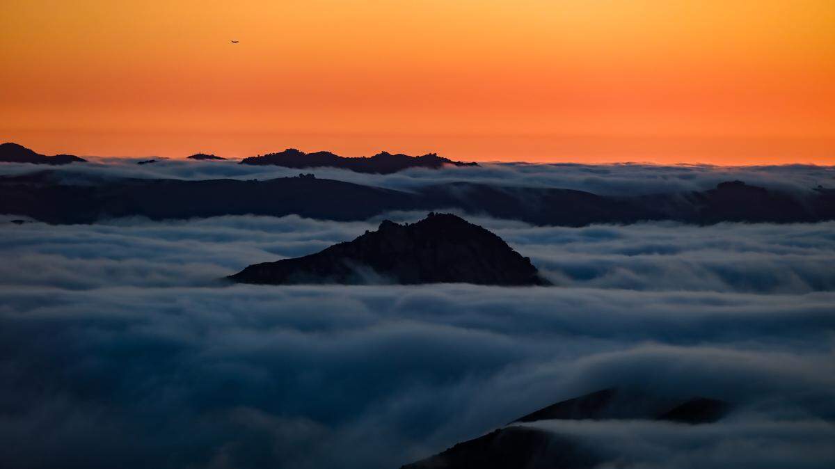 A thick layer of fog swirls around peaks in San Luis Obispo.