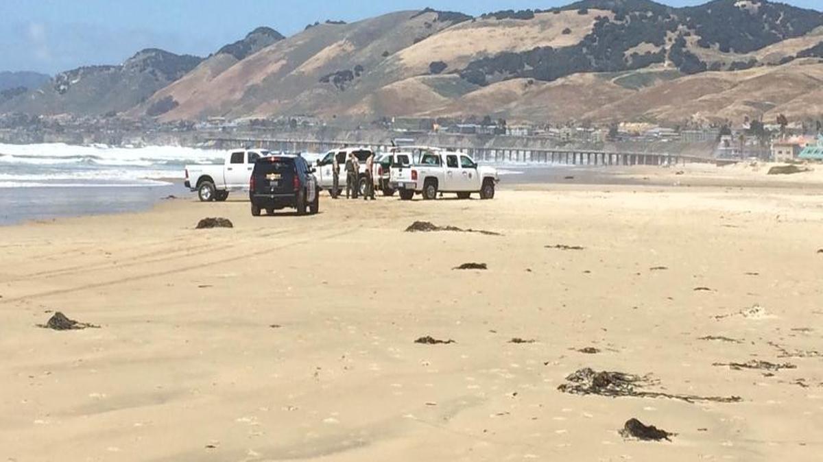 Sheriff’s investigators work at the location where the body of Marco Antonio Reyes Jr. washed up on Pismo Beach on Monday.