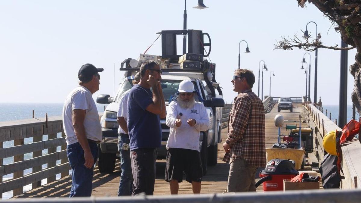 The Cayucos Pier reconstruction is near completion, with opening scheduled for Saturday. From left, Mark Schwind, Scott St. Clair (partially hidden), James Ottens, Steve Haugen and Graham Miguel discuss work on the structure last week.