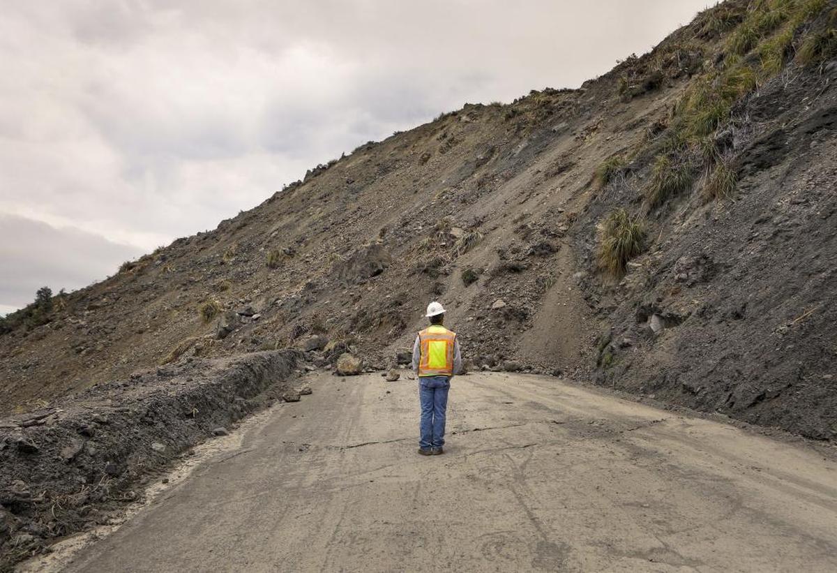 Bret Haney, construction inspector with Caltrans, is dwarfed by the massive mound of dirt on Wednesday, May 24, 2017, while examining the Mud Creek Slide on Highway 1.