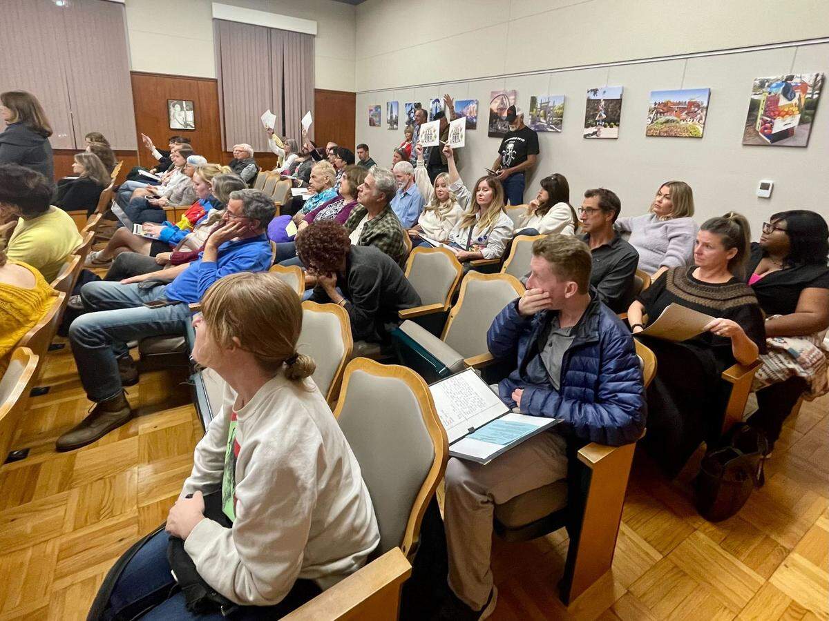 Attendees hold up signs at the San Luis Obispo City Council on Nov. 7, 2023, as speakers share how parking challenges were impacting the downtown.