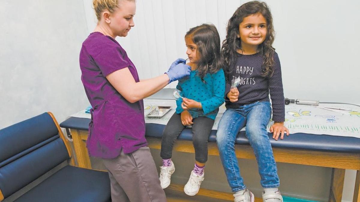 Medical assistant Kim Copeland, seen here in December 2014, gives flu shots and suckers to children at Dr. Rene Bravo’s office in San Luis Obispo.