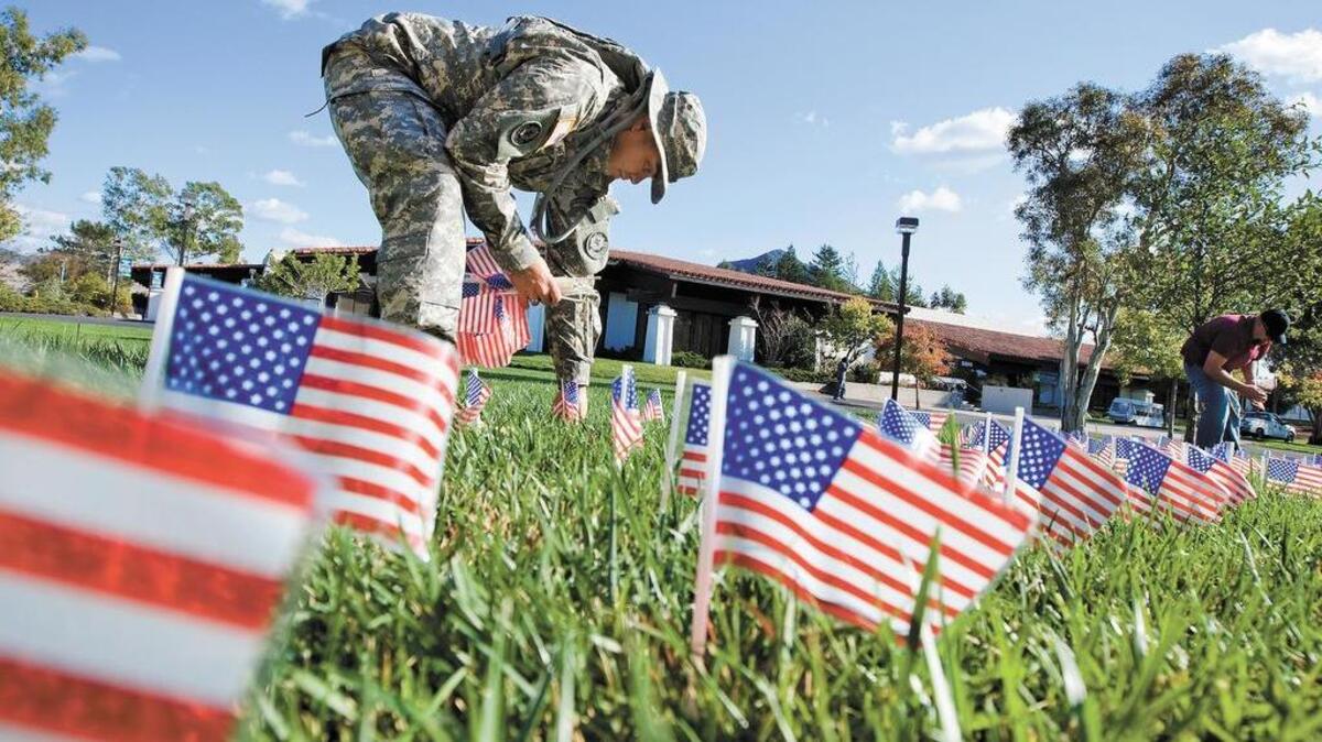 Ricardo Mediano, left, president of the Student Veterans Association of Cuesta College, and Monty Dodge, right, place flags in the lawn behind the college’s library in honor of Veterans Day in 2011.