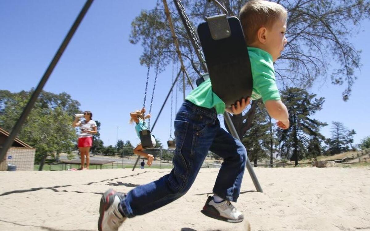 Noah Rubenstein, 5, takes a head-first approach to the swings, while Laura Mellow and her daughter Luli, 5, in the background, also enjoy Nipomo Community Park recently. Plans to expand most of the park facilities have been given the go-ahead.