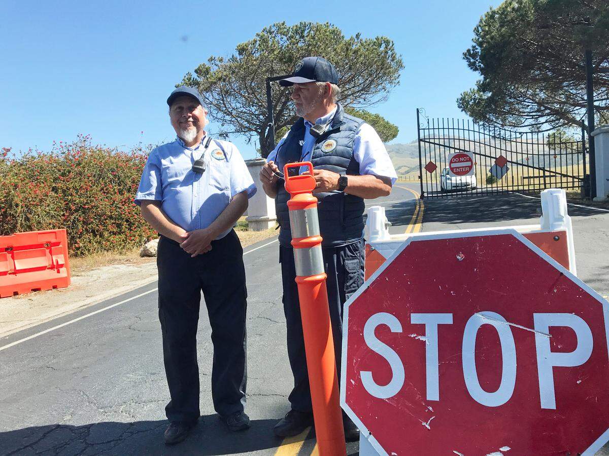 Hearst Castle day security guards Steve Brown, left, and Noah Snodgrass do gate duty on May 6, telling disappointed visitors that the state historical monument wouldn’t reopen for another five days. Reopening day, after more than two years of pandemic-and-road-repair closure, is May 11.